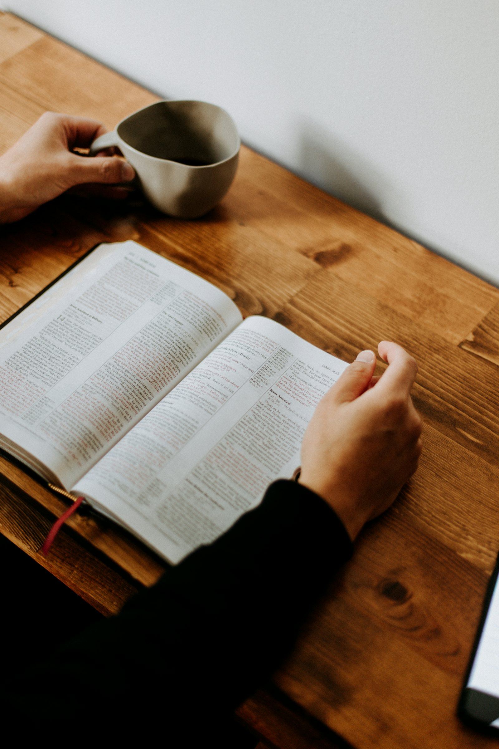 Offene Bibel und Kaffeetasse auf Holztisch