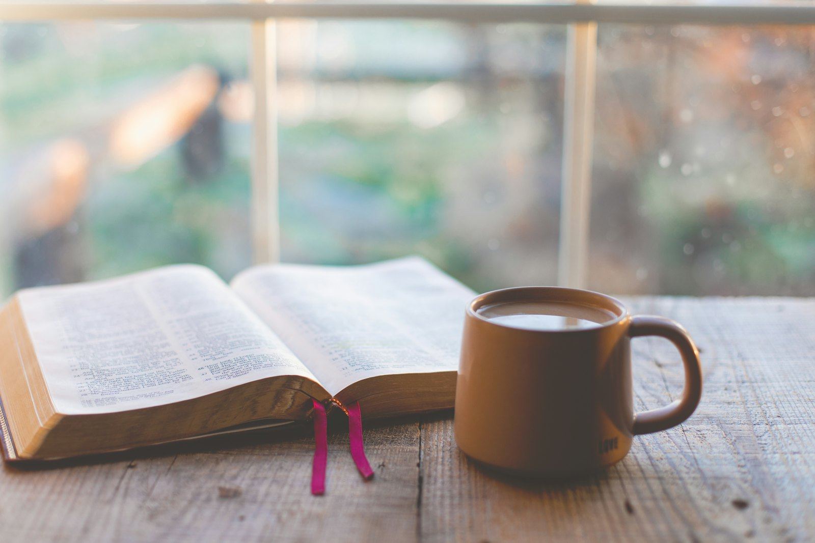 Bibel und Tasse im Morgenlicht am Fenster