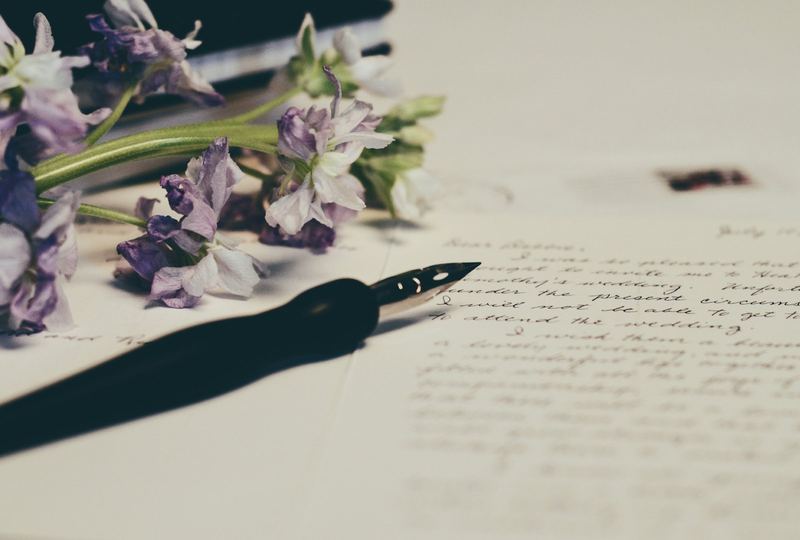 Füller und Blumen auf beschriebenem Papier